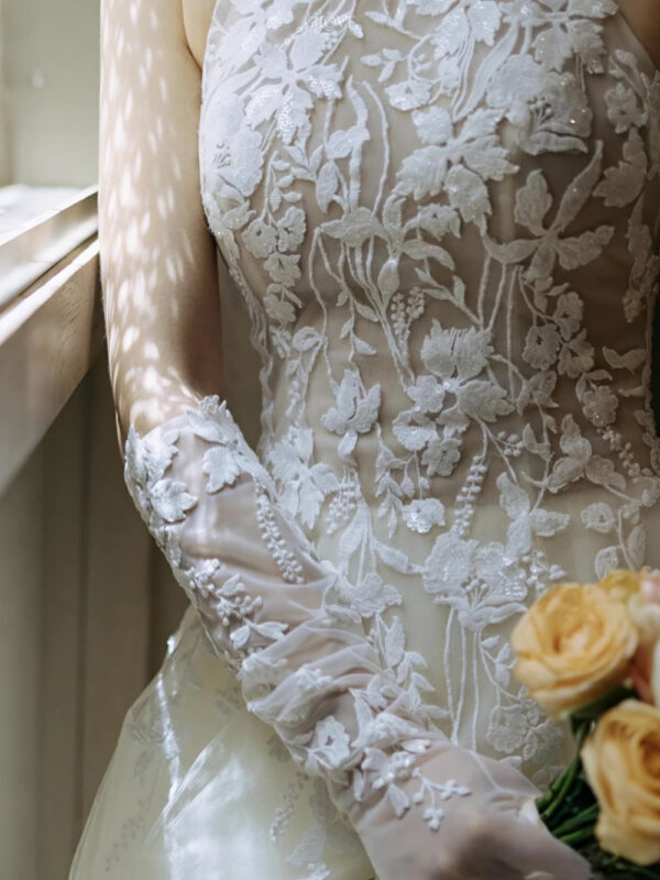 Váy cưới cổ yếm ren hoa nhẹ, dáng chữ A mềm mại, tôn vai và cổ cao.
